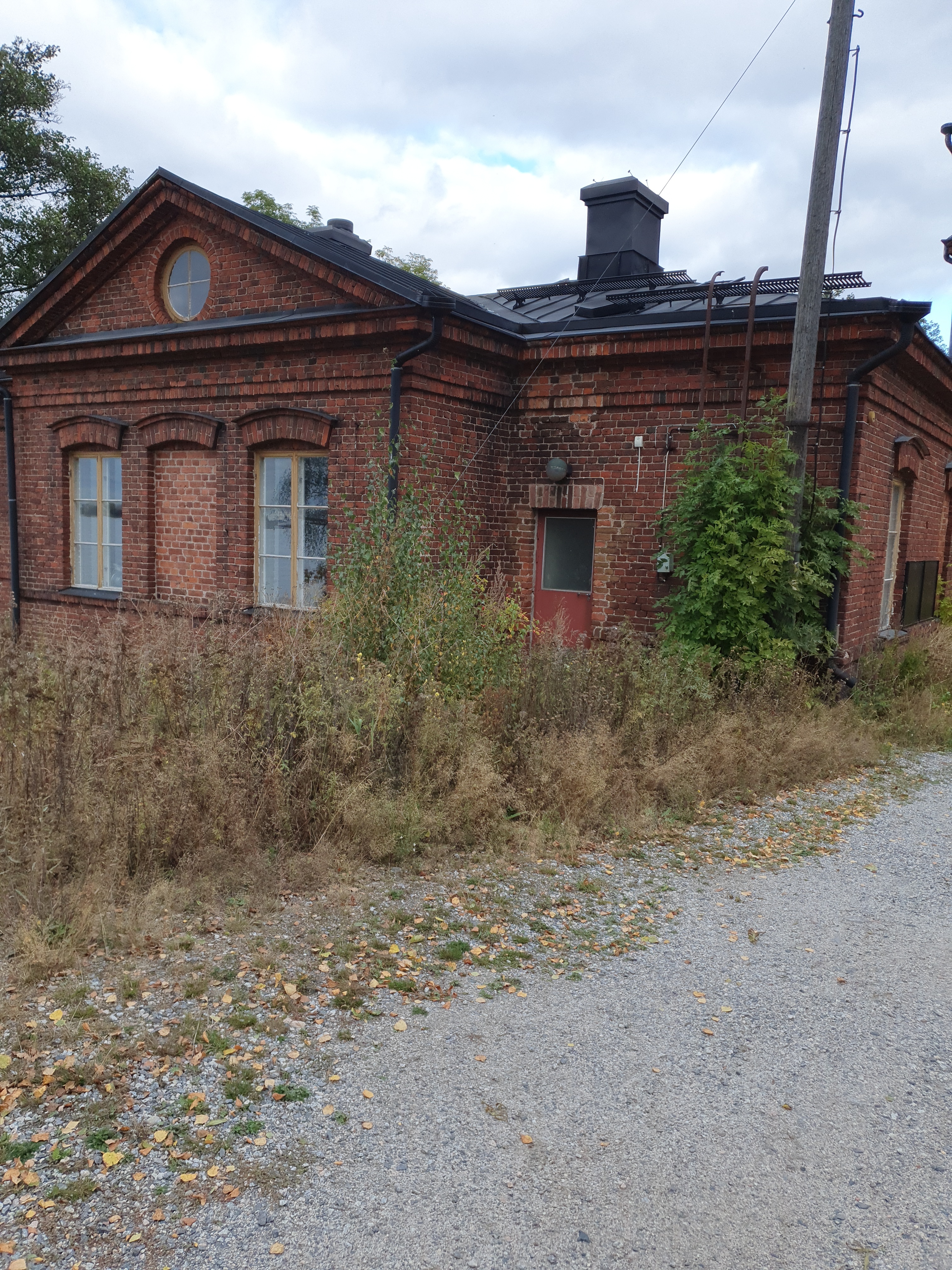 Vallisaarelaisia saaren luotsitalon pihapiirissä. Kaksi miehistä on sotilasunivormussa. Toisella naisista on sylissään pieni lapsi. Taustalla näkyvä tiilirakennus on luotsitalon sauna- ja pyykkitupa. rephoto