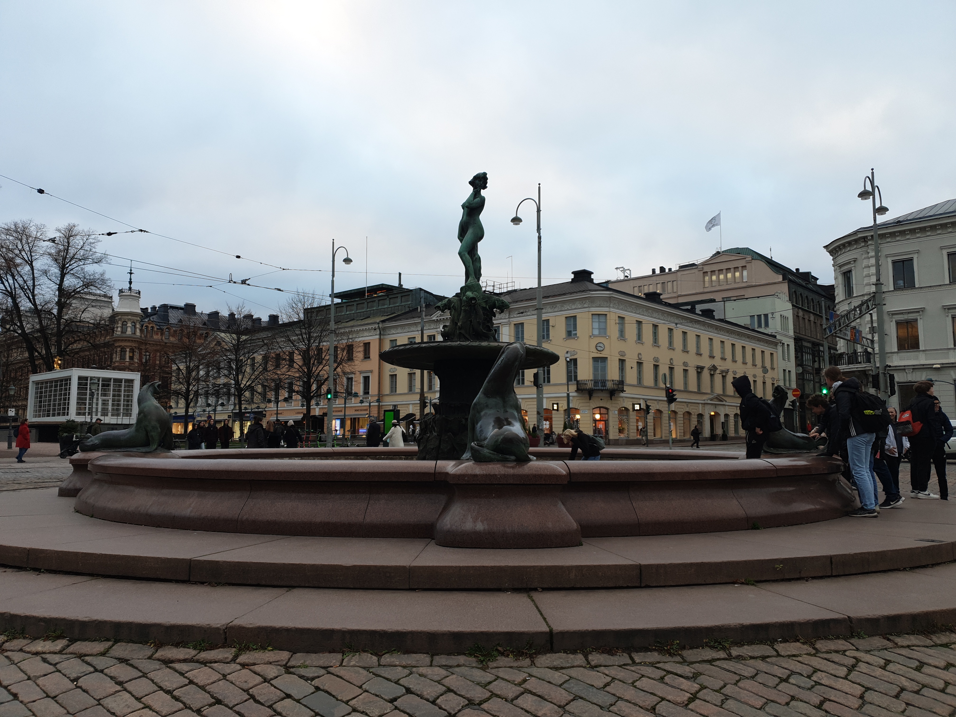 Havis Amanda -suihkukaivo Kauppatorilla paljastustilaisuuden jälkeen. Taustalla Pohjoinen Esplanaadikatu (Pohjoisesplanadi ) 19. - Unioninkatu 28. Kuvanveistäjä Ville Valgren 1908. Vrt. N269 rephoto