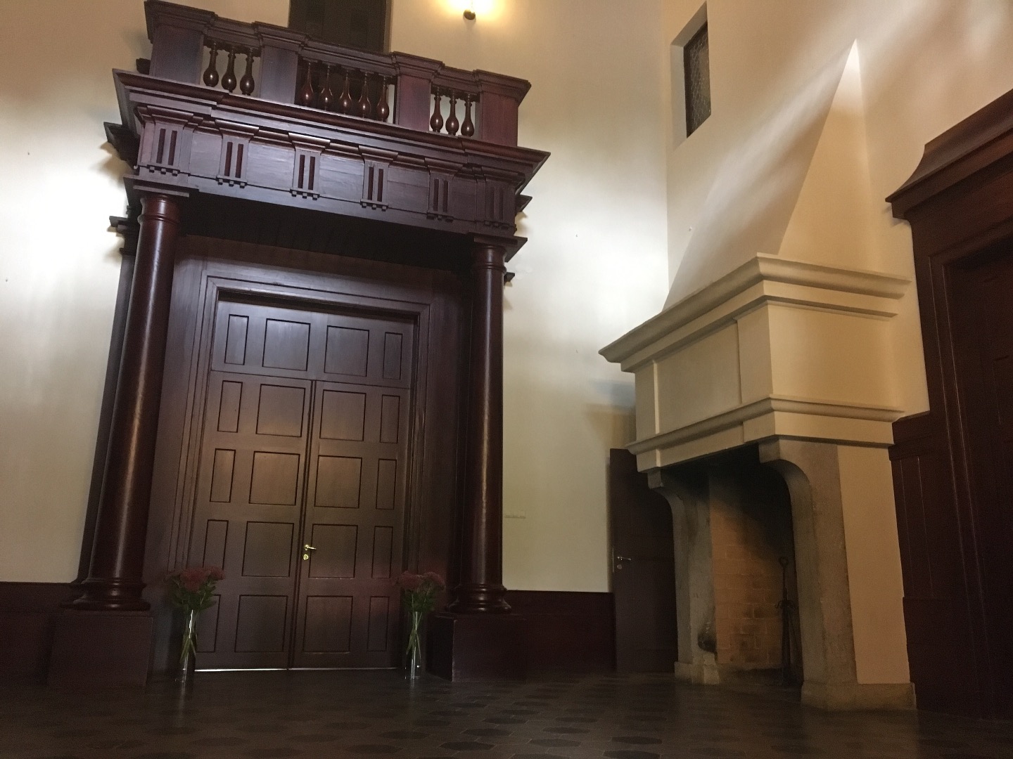 Alatskivi. The hall of the manor. On the left the dark door leads to indoors. On the right high white fireplace; on the white wall crocheted portraits of the manor owner's ancestors. rephoto