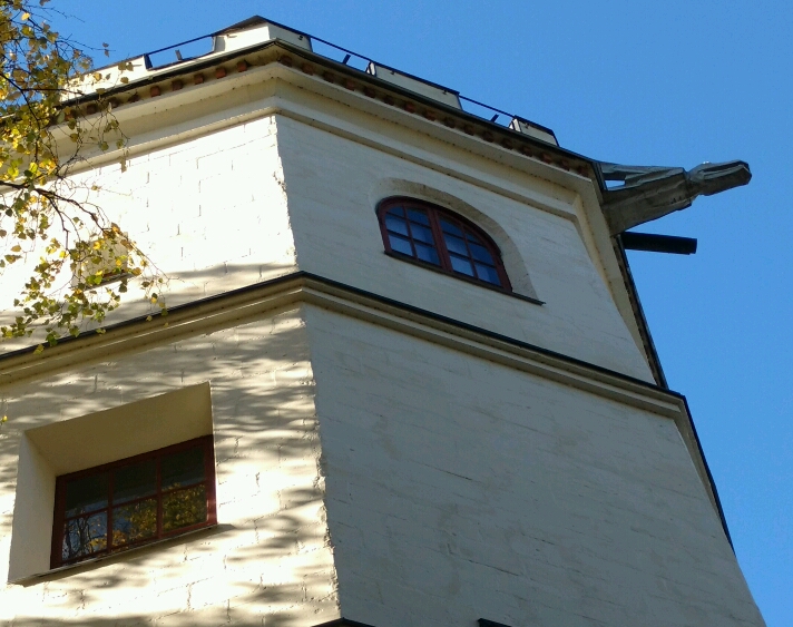 Akseli Gallen-Kallela on the tower of Tarvaspää working on a dragon-shaped gargoyle with his wife Mary watching, 1927. rephoto