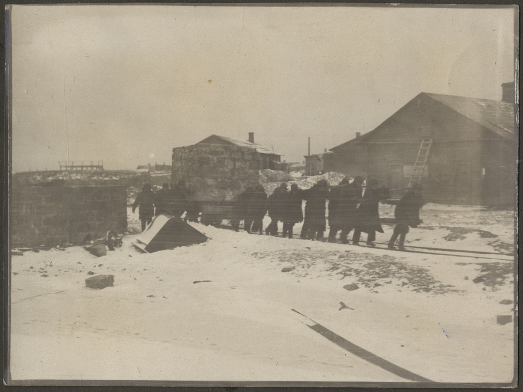 Foto Aleksander Peäske perekonnaalbumist: grupp inimesi väikest kaubavagunit koormaga vedamas