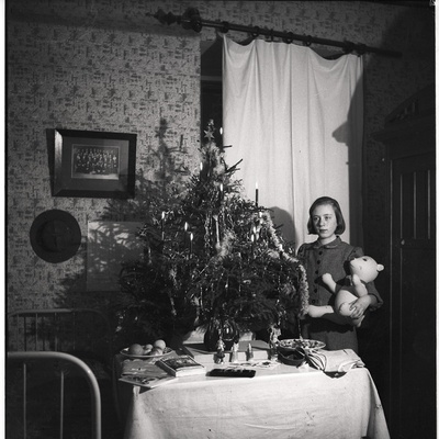 Ethel Malle Sarap hoidmas käes mängukaru, ees laud, taustal jõulukuusk  similar photo