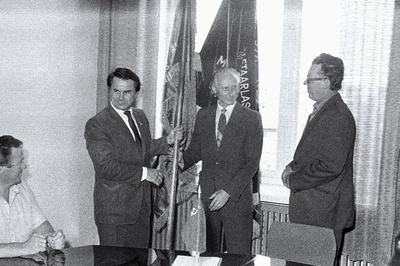 Tööstus, ehitus- ja transpordialase ülevabariigilise sotsialistliku võistluse eest rajoonide teises grupis 1983.a. II kvartalis Haapsalu rajoonile määratud EKP Keskkomitee, Eesti NSV Ministrite Nõukogu, Eesti NSV Ametiühingute Nõukogu, ELKNÜ Keskkomitee rändpunalipu annab rajooni tööstusaktiivi koosolekul EKP Haapsalu Rajoonikomitee I sekretärile E.Peeglile (keskel) üle EKP Keskkomitee ehituse ja linnamajanduse osakonna juhataja L.Ananitš.  duplicate photo