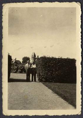 Feliks Siiman ja tundmatu mees seisavad liivatatud teel mingi hoone või hoonekompleksi sissekäigu juures heki kõrval  duplicate photo
