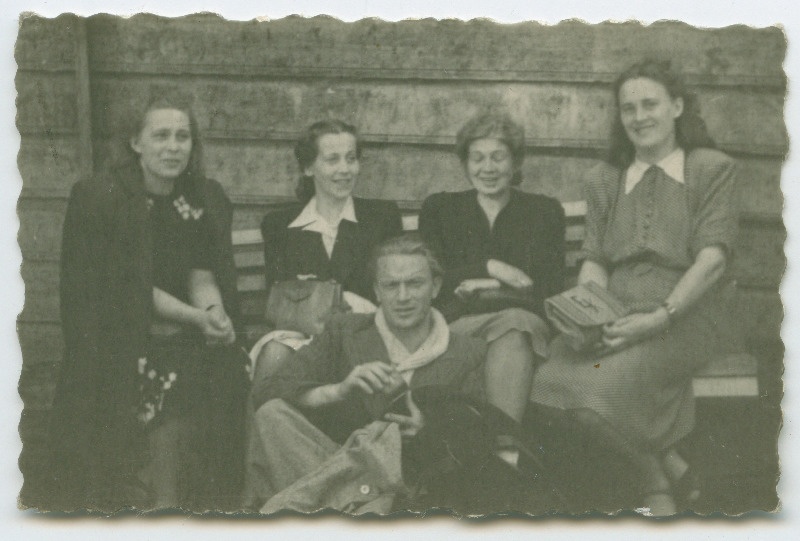 Priit Põltsama ja neli istumas majaseina ääres; naised istuvad pingil, Priit Põltsama maas nende ees