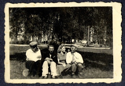 Neiu ja kolm noormeest istuvad pargis või puudesalus palgi peal  duplicate photo