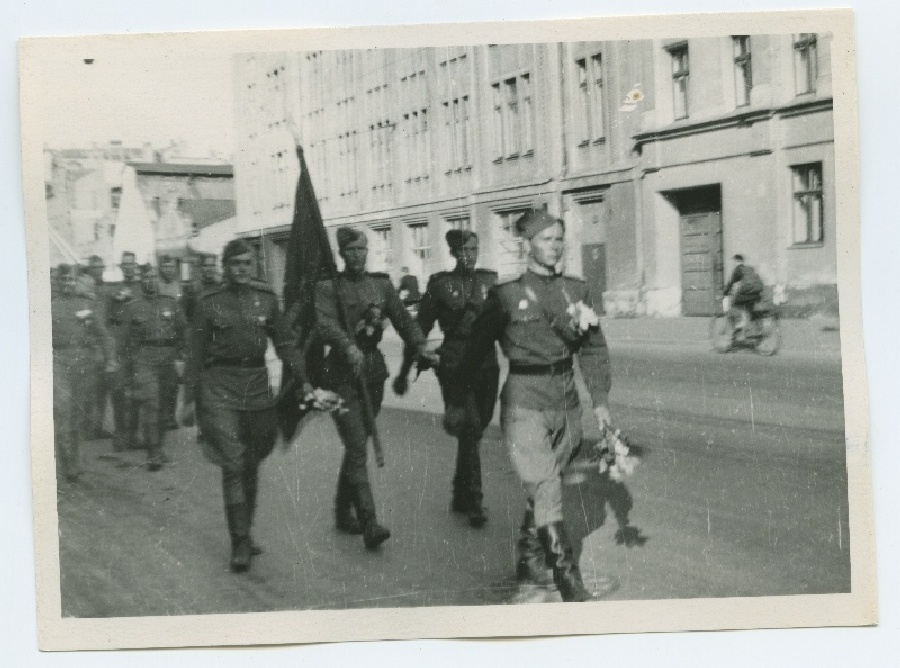 Eesti sõjaväelased saabuvad Riiga, 1945. aastal. Ees sammub vanemleitnant Soomre, tema järel NSV Liidu kangelane Hindreus, lipukandja Erich Pilliroog.