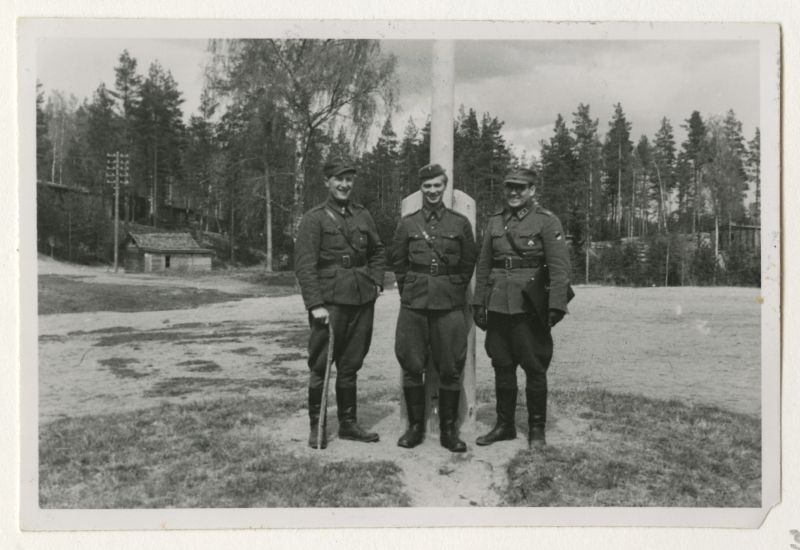 Grupipilt laagri lipumasti kõrval. 3 meest. Soomepoisid Jalgala laagris 1943.a.