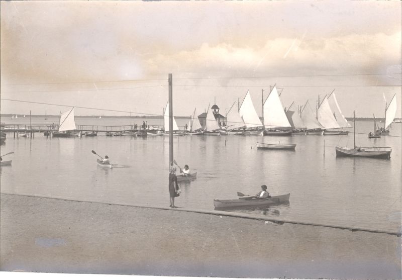 Foto. Paadisild Haapsalu Suure Promenaadi ääres ja aerutajad lahel. 20. saj algus.