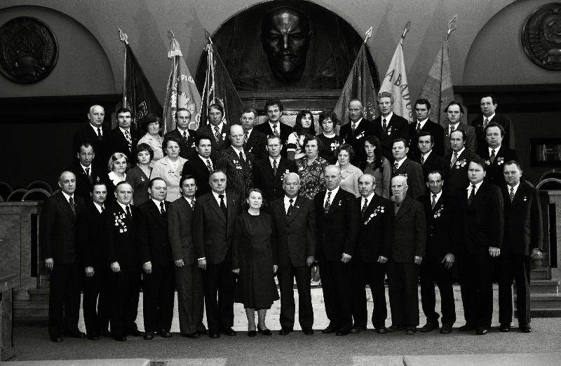 Eesti NSV Ehitusministeeriumi süsteemi töötajate, sotsialistliku võistluse võitjate pildistamine revolutsiooni-, lahingu- ja töökuulsuse lippude juures Eesti NSV Ministrite Nõukogu valges saalis seoses Suure Sotsialistliku Oktoobrirevolutsiooni 60. aastapäeva tähistamisega, Eesti NSV Ehitusministeeriumi Tallinna Elamuehitusministeeriumi Tallinna Elamuehituskombinaadi brigadirid, sotsialistliku töö kangelane L. Vammus, J. Komarov, A. Valgepea, monteerija V. Voit, ülem G. Švartser, töötaja H. Knut; Tallinna Ehitustrusti Ehitusvalitsuse nr 1 krohvija N. Kornienko, brigadir V. Onna, vanemtöödejuhataja O. Randman;  jätkub: Tallinna Ehitustrusti Ehitusvalitsuse nr 2 müürsepp N. Balatšuk, Tallinna Ehitustrusti Ehitusvalitsuse nr 5 maaler N. Vzmõslova, Tallinna Ehitustrusti Ehitusvalitsuse nr 4 brigadir V. Mõnzu, Tallinna Ehitustrusti Ehitusvalitsuse nr 8 brigadir M. Odõnets; Tartu Ehitustrusti Ehitusvalitsuse nr 1 brigadirid U. Kõllamõts ja L. Limberg; Tartu Elamueh