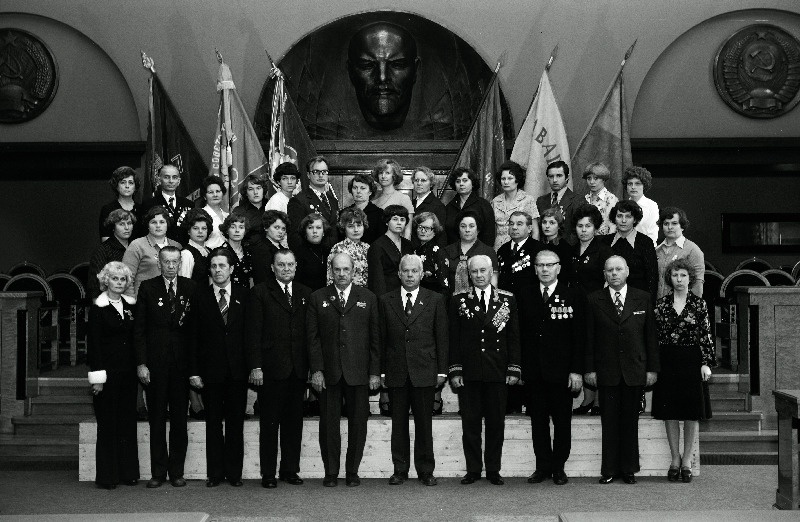 Eesti NSV Kaubandusettevõtete ja organisatsioonide töötajate, sotsialistliku võistluse võitjate pildistamine revolutsiooni-, lahingu-ja töökuulsuse lippude juures Eesti NSV Ministrite Nõukogu Valges saalis seoses Suure Sotsialistliku Oktoobrirevolutsiooni 60. aastapäeva tähistamisega. Tallinna 1. Toidukaubastu kaupluse Tuluke filiaali osakonnajuhataja, Eesti NSV teeneline kaubandustöötaja Asta Allmere, Tallinna Tööstuskaubastu kaupluse nr. 54 vanemmüüja Ode Liit, Kohtla-Järve Kaubandusvalitsuse kaupluse Narva juhataja, Eesti NSV teeneline kaubandustöötaja Serafima Maloševa, Tallinna Tööstuskaubastu kaupluse Mood juhataja,    jätkub: Eesti NSV teeneline kaubandustöötaja Dea Oja, Kohtla-Järve Kaubandusvalitsuse restorani Ahtme kokk Anna Adasko, Tallinna 2. Toitlustustrusti restorani Kevad kokk Maili Anari, Tartu Kaubandusvalitsuse kaupluse Karete vanemkontrolör -kassapidaja Kaie Arand, Narva Kaubandusvalitsuse parteikomitee sekretär Anatoli Bolšakov, Kohtla-J