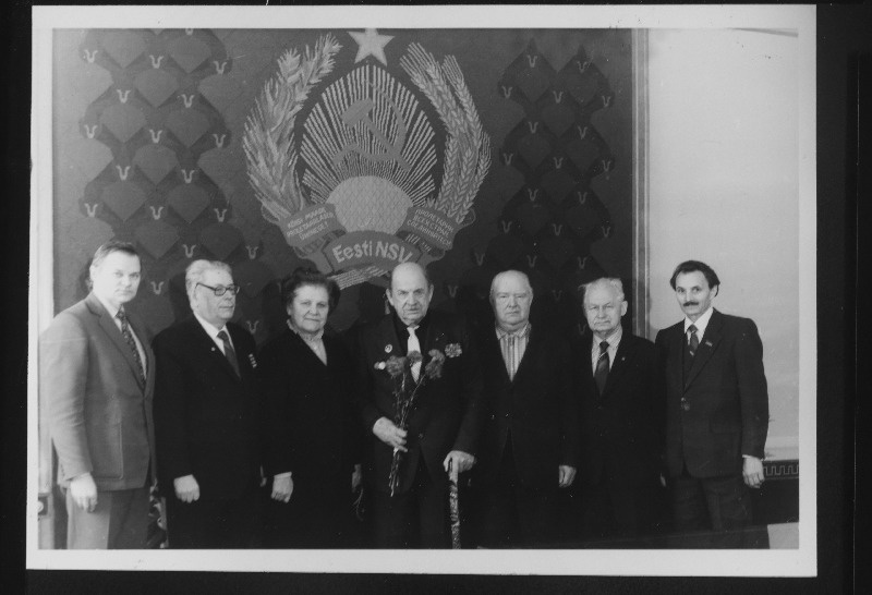 Eesti NSV Ülemnõukogu Presiidiumi aukirjaga autasustatud kodusõja, Suure Isamaasõja ja parteiveteran Geindrich Gustavson (keskel) Eesti NSV Ülemnõukogu Pesiidiumis. Vasakult 3. Eesti NSV Ülemnõukogu Presiidiumi esimehe asetäitja Meta Vannas, 7. Eesti NSV Ülemnõukogu Presiidiumi sekretär Viktor Vaht.