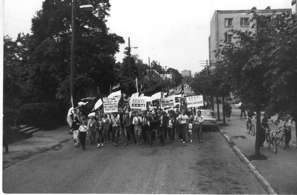 Foto. 23. juunil 1988.a. Vaba-Sõltumatu Noortekolonn nr. 1 ning ERSP-lased liiguvad Võru kalmistult Kreutzwaldi tänavat mööda Roosisaarele jaanipäeva pidama. Esimeses reas paremalt Ants Pindis, Maris Sarv, Mati Vilu, Arvo Pesti, keskel lipuga Tiit Tens Põlvast