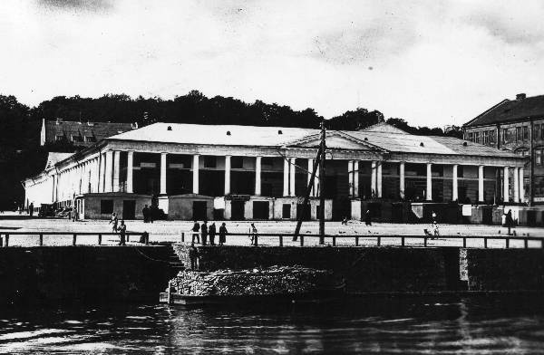 Emajõe kaldapealne ja Kaubahoov (esifassaad ja Kauba t poolne külgfassaad). Küttepuude lastiga paat jõel. Tartu, 1927. Repro: E. Selleke.