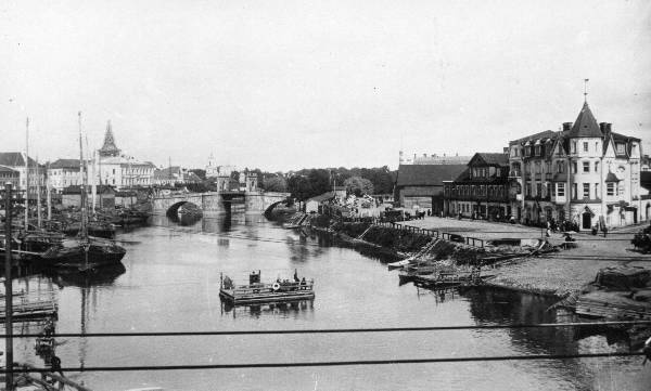 Tartu kesklinn Emajõe parem- ja vasakkaldal. 
Esiplaanil Emajõe üleveoparv Uueturu ja Holmi t joonel. Taga Kivisild.
Paremal hotelli "Jakor" hoone ( juugendstiil, arh. R. von Engelhardt, 1905), eemal kino "Illusion" hoone. Vasakul lodjad. 
Tartu, ca 1910.