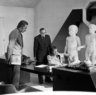 Tallinnfilmi mängufilmi "31. osakonna hukk" I seeria. Seisavad Jensen (Lembit Ulfsak) ja I direktor (Heino Mandri), istub kirjastaja (Ago Roo). Kaadris Ülo Õuna skulptuur "Isa ja poeg".  similar photo