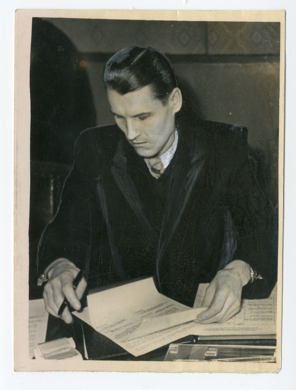 Foto, must-valge. Lehti allkirjastav mees