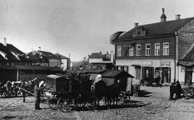 Postijaama plats Riia mäel.
Esiplaanil puuputkad ja hobuvankrid mitmesuguse kraamiga. Paremal pool (Pihkva t; hilisem Võru mnt) asetsevatel majadel eesti- ja venekeelsed sildid: Vürtsi kauplus; Õlle pood
Vaade postijaama poolt kesklinna suunas.  Tartu, 20. saj. algus.  duplicate photo