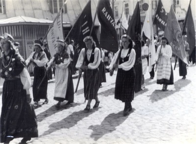 Foto. Läänemaa laulupeo rongkäik Haapsalus Karja t. 5 maja nurgal. Esiplaanil rahvariides naised. 1947.  similar photo