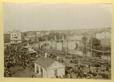 Turg Emajõe paremkaldal: kaalumaja, lodjad. Taga Kivisild, auvärava torn silla juures. Tartu, 1880-1900.