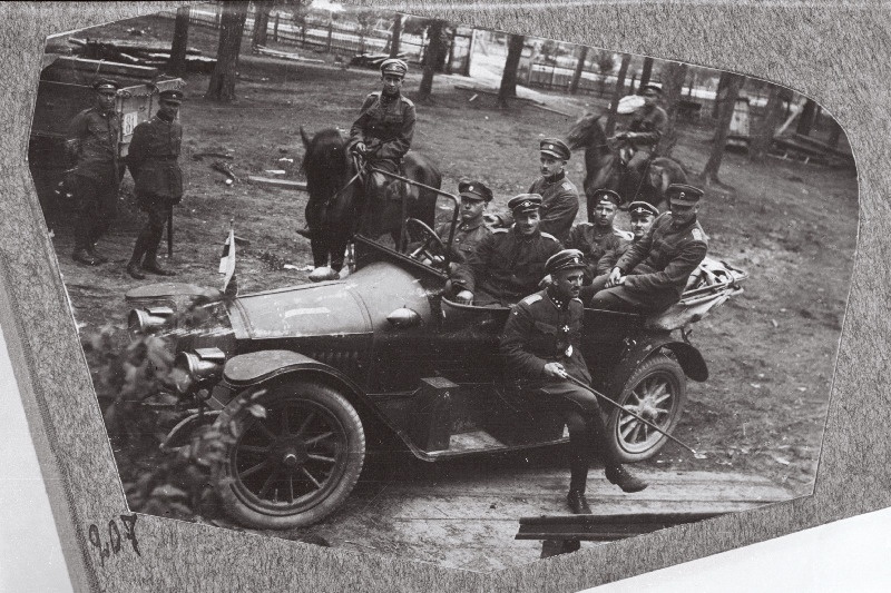 Vabadussõda. 6.Jalaväepolgu staabiohvitserid Rodenpoisis (Ropaži). Veoauto juures vasakult 2. kortermeister sõjaväeametnik Karl Lossmann, vasakpoolsel hobusel vanemkäsundusohvitser alamleitnant Aleksander Häelme, autojuhi kõrval komandandikomando ülem lipnik Joann Fuks (Kalda), autos keskel vasakul polguülema käsundusohvitser leitnant Bruno Vitas, autos keskel paremal polgu adjutant leitnant Aleksander Kulbusch (Kulgver), auto tagaistmel vasakul adjutanti abi veltveebel Georgi Bachmann (Jüri Randla), auto tagaistmel paremal polguülema abi alamkapten Egbert Jürmann, auto astmel istub polguülem kapten Karl Tallo.