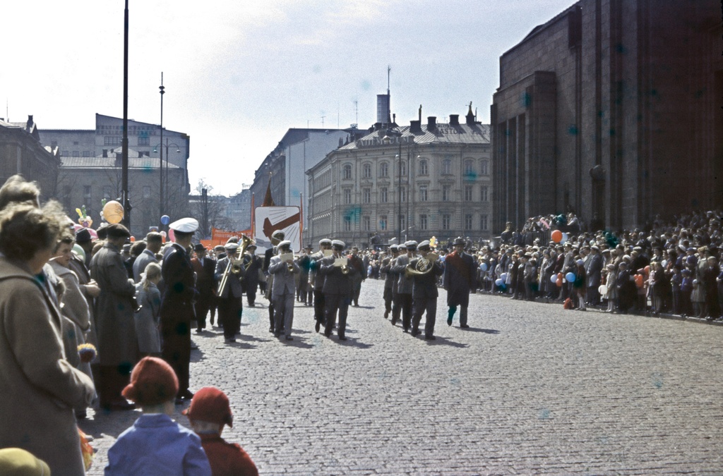 Työväen vappukulkue Helsingin rautatieaseman edessä liikkumassa kohti Kaisaniemen kentällä pidettävää vappujuhlaa, edessä puhallinorkesteri.