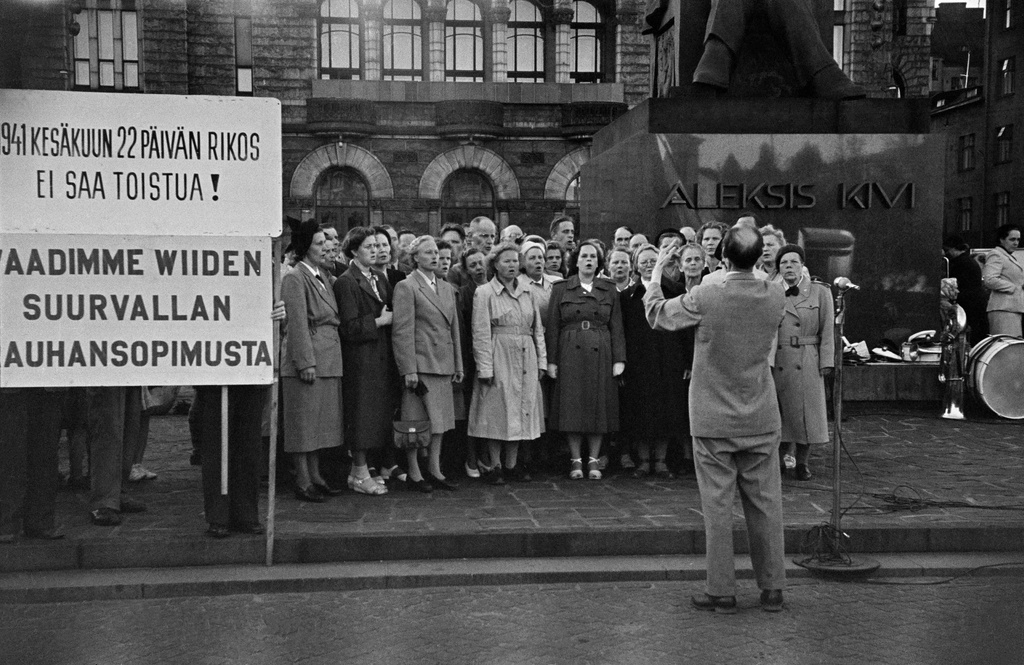 Mielenosoitus Rautatientorilla, kuoro esiintyy. Vasemmalla kyltti jossa teksti "1941 kesäkuun 22. päivän rikos ei saa toistua! Vaadimme wiiden suurvallan rauhansopimusta".