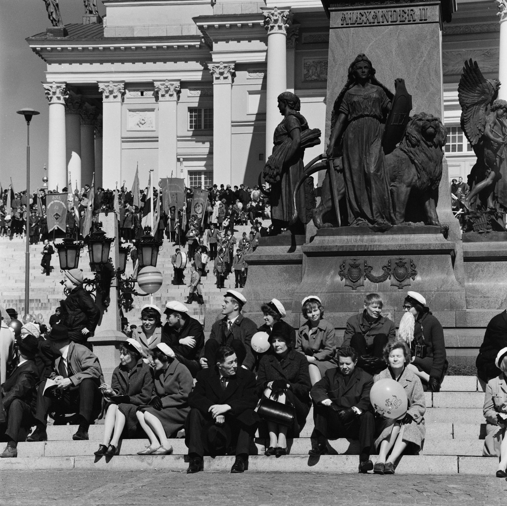 Kommunistien vappujuhla Senaatintorilla. Ihmisiä istumassa Aleksanteri II:n patsaan juurella.