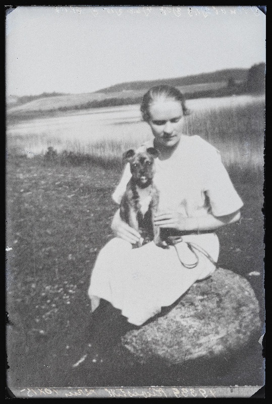 Naine koeraga veekogu ääres kivil istumas, (14.09.1927 fotokoopia, tellija Kivistik).