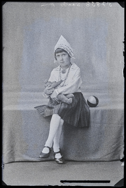 Sootsi rahvuslikes riietes tütar mängukaruga.