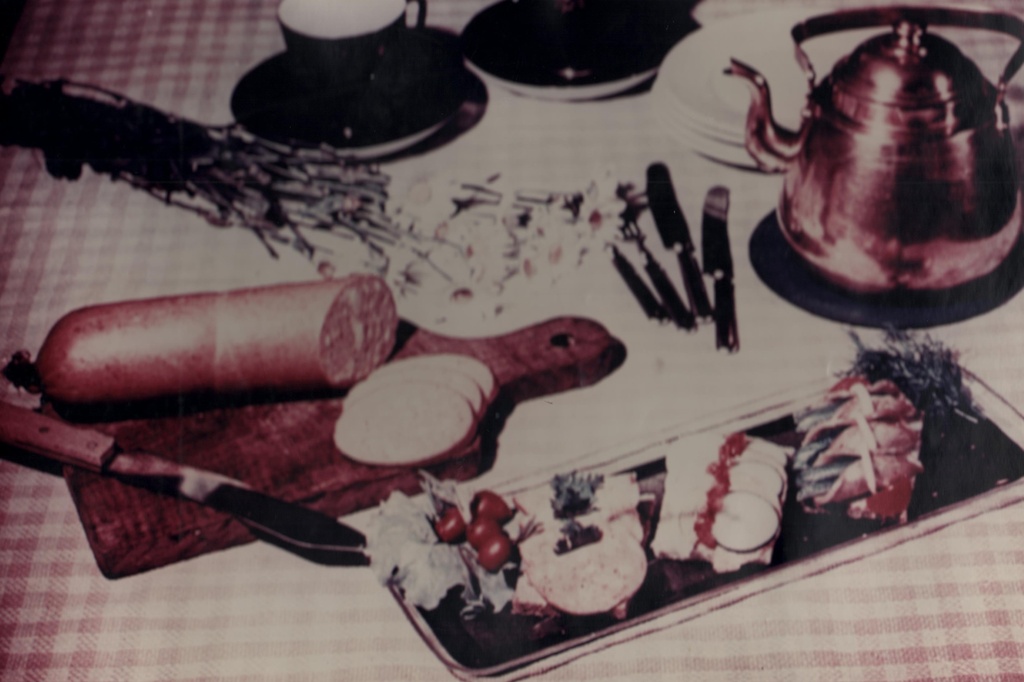 Laual teetassid ja teekann, karikakrad, lõikelaual keeduvorst viilutatud, serveeritud vaagnale