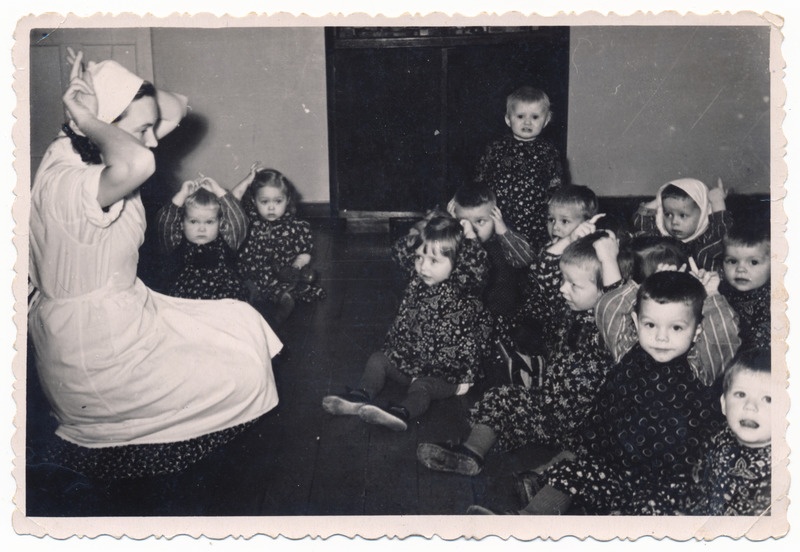foto Viljandi linavabriku lastesõim, A. Maramaa pst 5, sisevaade, kasvataja, lapsed (sõimeriided), sügis 1956