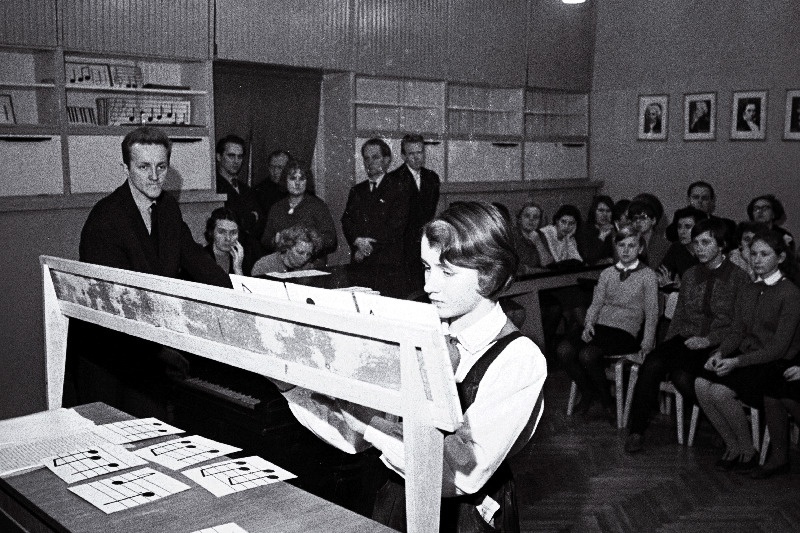 Tallinna Linna TSN Täitevkomitee haridusosakonna metoodilise kabineti muusikaõpetajate ainesektsiooni esimees, Tallinna 39. keskkooli muusikaõpetaja Koit Kirber (vasakult 1.) kooli muusikaklassis Tallinna lauluõpetajate omakonstrueeritud noodiõpetuse abivahendit- noodilotot demonstreerimas.