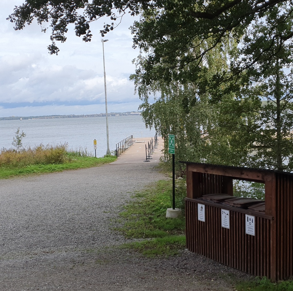 Väkeä Vallisaaren Päälaiturin luona. Ihmiset jonottavat pääsyä vartiolle näyttääkseen kulkulupansa saavuttuaan veneellä saareen. Vallisaari oli alunperin venäläisen varuskunnan käytössä ollut saari ja Suomen itsenäistymisen jälkeen Suomen armeijan käytössä, ja siten pääsy saarelle oli luvanvaraista. Valokuva on otettu saaren pohjoisrannasta. On kevät ja maassa on vielä jäämiä lumesta ja jäästä. rephoto