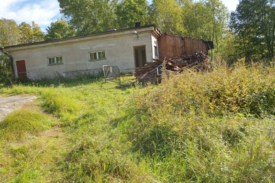 Paloaseman palokalustovaja Vallisaaressa. Siinä säilytettiin aikanaan T-mallista Fordia, kuorma-autoa ja hevosvetoisia kärryjä. Keskimmäisestä ovesta kuljettiin kahden hevosen talliin ja viereisestä punaisesta ovesta hevosten rehu- ja heinävarastoon. Pihapiiriin kuuluu myös vasemmassa reunassa näkyvä puusepänverstas. Valokuva on otettu aurinkoisella säällä. rephoto