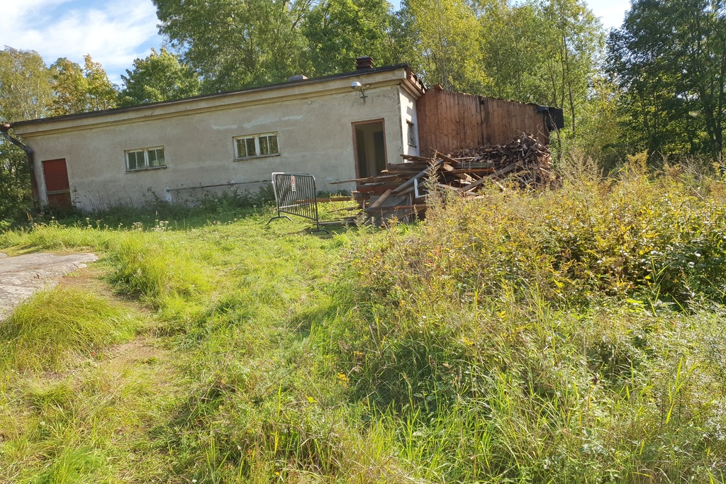 Paloaseman palokalustovaja Vallisaaressa. Siinä säilytettiin aikanaan T-mallista Fordia, kuorma-autoa ja hevosvetoisia kärryjä. Keskimmäisestä ovesta kuljettiin kahden hevosen talliin ja viereisestä punaisesta ovesta hevosten rehu- ja heinävarastoon. Pihapiiriin kuuluu myös vasemmassa reunassa näkyvä puusepänverstas. Valokuva on otettu aurinkoisella säällä. rephoto