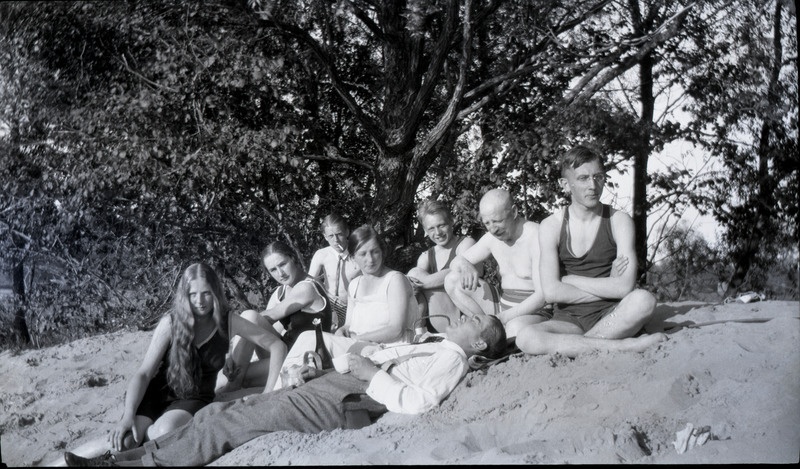 Kaheksa inimest supelriietes istumas ning pikniku pidamas.