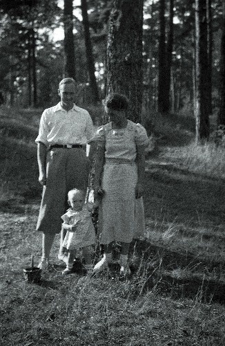 Mees, naine ja väike laps männimetsas.