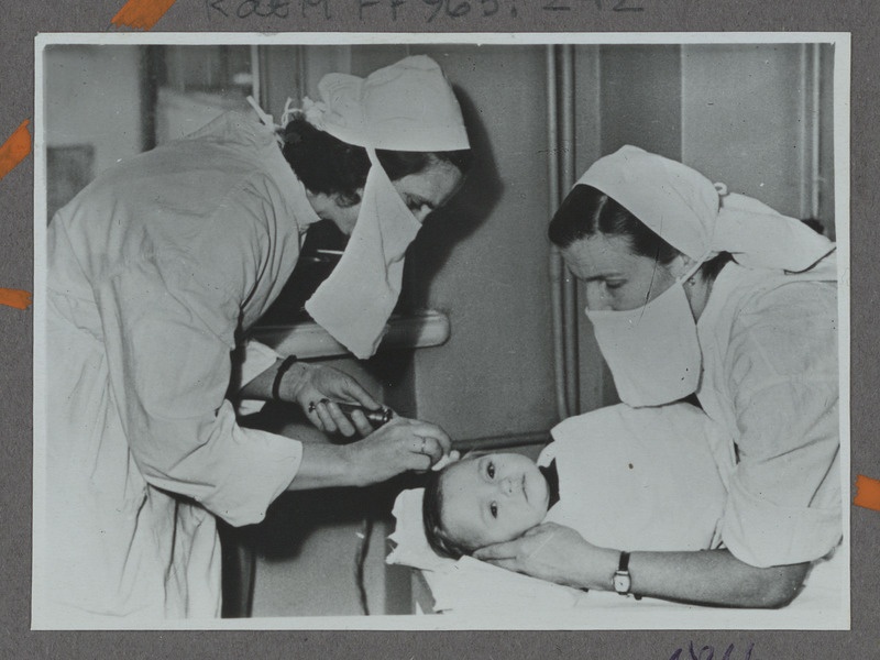Eesti raudtee: Tallinna Raudteelaste Lastehaigla vanem-meditsiiniõde Irene Kikas süstib aastast patsienti Galjat, 1959, foto: Oskar Sildam