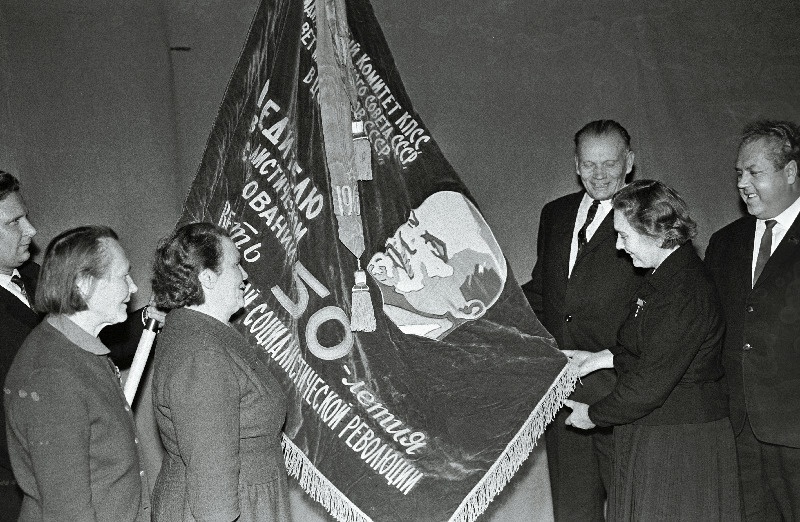 Kolhoosi Estonia (vasakult) lüpsja-karjatalitaja, kahe Lenini ordeni omanik H. Mäsak, sotsialistliku töö kangelased lüpsja-karjatalitaja E. Mihkelson, majandi esimees H. Marrandi ja farmijuhataja P. Käsper ning EKP Keskkomitee teine sekretär A. Vader Suure Sotsialistliku Oktoobrirevolutsiooni 50. aastapäeva eelse sotsialistliku võistluse võitjatele antud mälestuslipu juures.