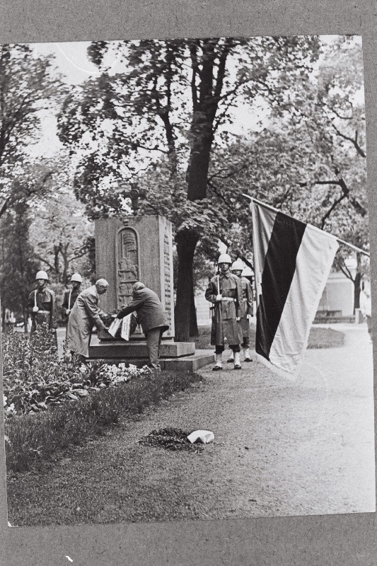 Eesti Akadeemilise Sõjaajaloo Seltsi liikmed ja 1943 - 1944.a. Soome jätkusõjast osavõtnud Eesti Vabatahtlike külaskäigul Soome asetatakse pärg Eesti Vabadussõjast osavõtnud Soome vabatahtlike mälestussambale. Esiplaanil Eesti Akadeemilise Sõjaajaloo Seltsi lipp.