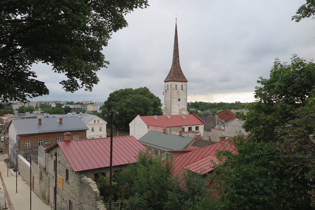 Vaade Rakvere Kolmainu kiriku tornile vallimäelt - Rakvere Kolmainu kiriku torn paistab üle muinsuskaitseala hoonete katuste, taamal linna korrusmajad.