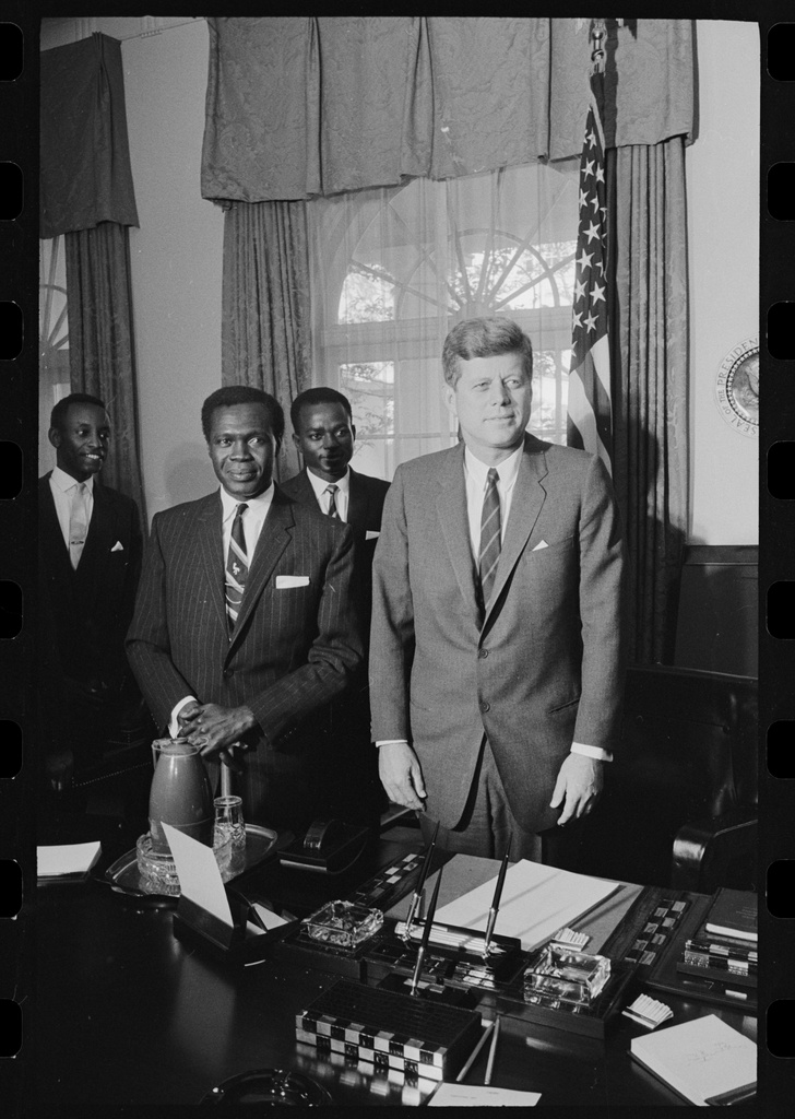 President John F. Kennedy with Prime Minister Milton Obote - NSC, Congressional - JFK and Milten Obote (Uganda). President John F. Kennedy and Prime Minister Milton Obote in the Oval Office. Grace Ibingira stands at the far left, and John Kakonge stands between Obote and Kennedy.