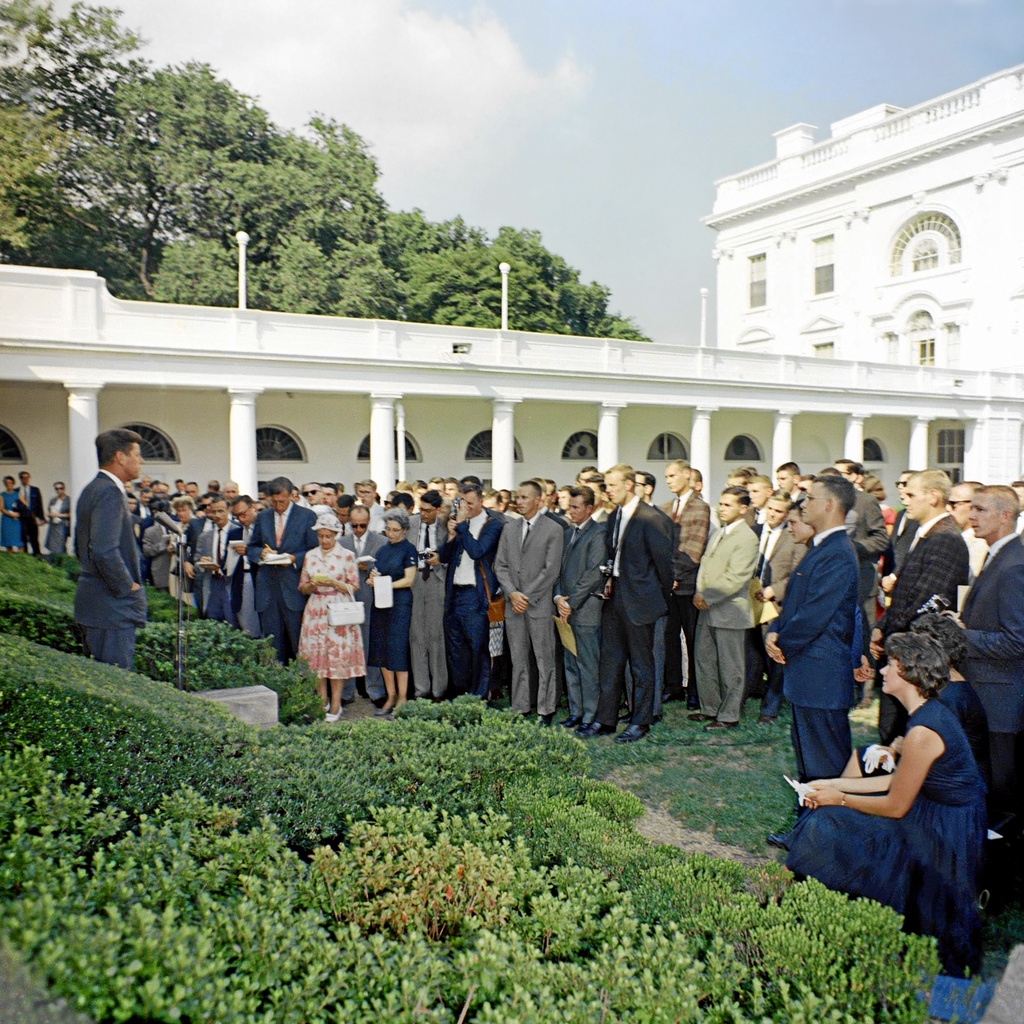 Kennedy Peace Corps group 1961 B003a (retouched) - August 28, 1961 - President Kennedy hosts a ceremony at the White House Rose Garden in honor of the first groups of Peace Corps Volunteers departing for service in Ghana and Tanzania. Two days later, the first group of 51 Peace Corps Ghana Volunteers arrived in Accra, Ghana to serve as teachers.