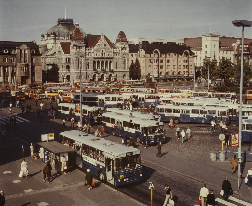 {'fi': 'Rautatientorin bussilaiturit, taustalla Kansallisteatteri.', '_type': 'lang'} - Rautatientorin bussilaiturit, taustalla Kansallisteatteri; vedos, muovipaperi, väri