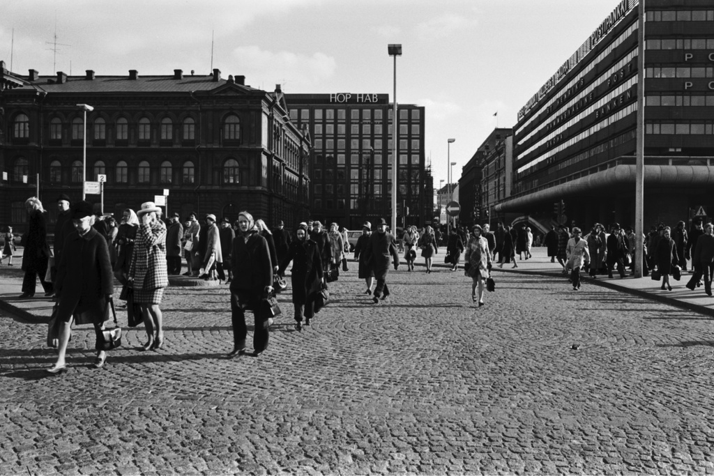 {'fi': 'Keskuskadun suunnalta tulevia jalankulkijoita iltapäivän ruuhka-aikaan Rautatientorilla', '_type': 'lang'} - Keskuskadun suunnalta tulevia jalankulkijoita iltapäivän ruuhka-aikaan Rautatientorilla. Vasemmalla Ateneumin rakennus, oikealla Makkaratalo. -- negatiivi, filmi, mv