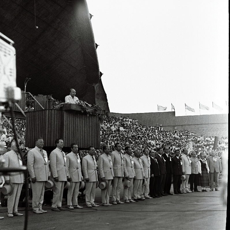 Juubelilaulupeo üldjuhid (vasakult): 1. V. Lemmik (?), 2. L. Karindi, 3. K. Areng, 4. A. Pajupuu, 5. H. Uibo, 6. A. Stepanov, 7. A. Velmet, 8. A. Kiilaspea, 9. H. Rannap, 11. J. Tungal, 12. N. Järvi, 13. H. Orusaar, 14. U. Järvela (?), 15. A. Ratassepp, 16. H. Kaljuste, 17. L. Verlin. Kõneleb üldlaulupeo peakomisjoni esimees A. Green.