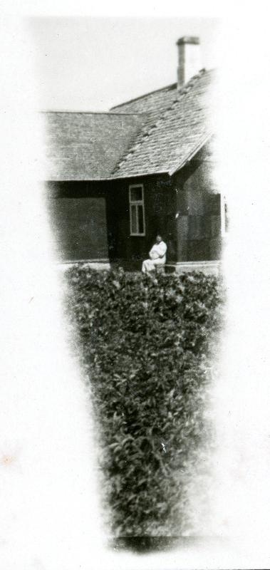 Taluhoone ees istuv tundmatu mees, osa fotost