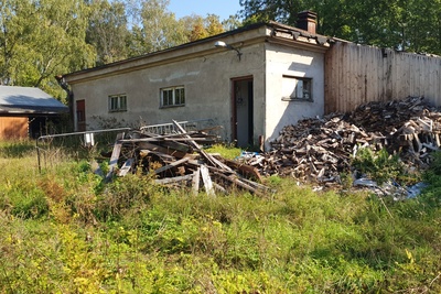 Paloaseman palokalustovaja Vallisaaressa. Siinä säilytettiin aikanaan T-mallista Fordia, kuorma-autoa ja hevosvetoisia kärryjä. Keskimmäisestä ovesta kuljettiin kahden hevosen talliin ja viereisestä punaisesta ovesta hevosten rehu- ja heinävarastoon. Pihapiiriin kuuluu myös vasemmassa reunassa näkyvä puusepänverstas. Valokuva on otettu aurinkoisella säällä. rephoto