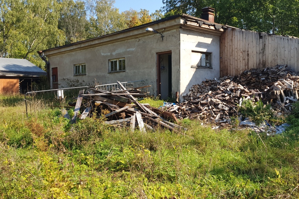 Paloaseman palokalustovaja Vallisaaressa. Siinä säilytettiin aikanaan T-mallista Fordia, kuorma-autoa ja hevosvetoisia kärryjä. Keskimmäisestä ovesta kuljettiin kahden hevosen talliin ja viereisestä punaisesta ovesta hevosten rehu- ja heinävarastoon. Pihapiiriin kuuluu myös vasemmassa reunassa näkyvä puusepänverstas. Valokuva on otettu aurinkoisella säällä. rephoto